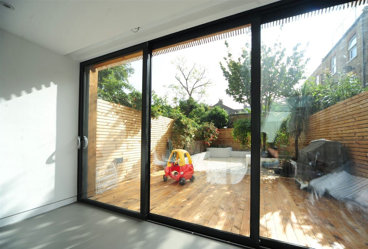 Black-framed aluminium sliding doors opening onto a decked garden
