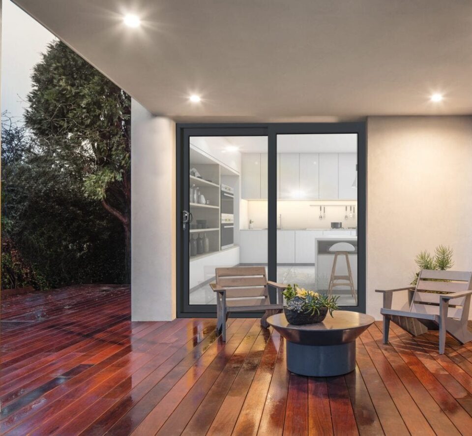 Anthracite grey sliding patio doors opening onto a decked terrace at dusk