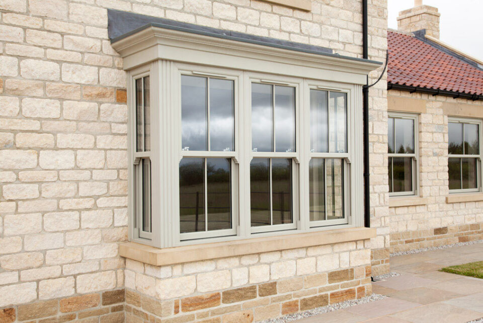 Grey sliding sash bay window on a stone cottage